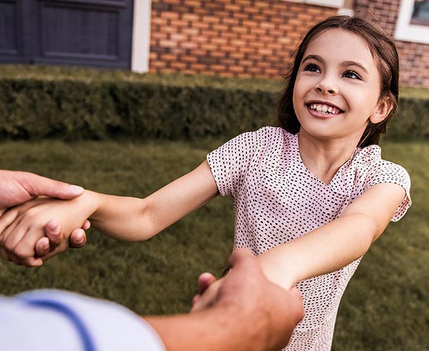 little-girl-holding-fathers-hands-in-yard