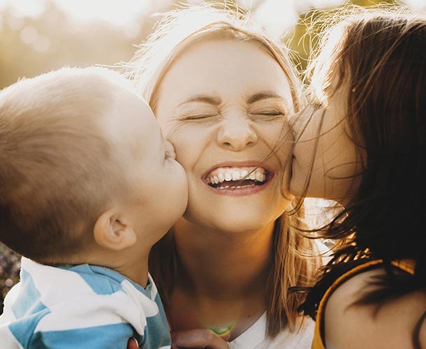 two-children-kissing-moms-cheeks
